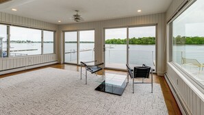 A spacious room with large windows, a ceiling fan, and a view of a lake. - Hull Bay Waterfront Home: Private Dock & Apartment (Hull)