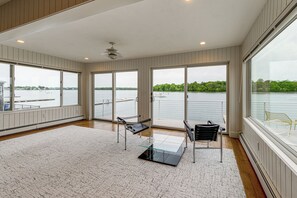 Ein geräumiges Zimmer mit großen Fenstern, einem Deckenventilator und Seeblick.