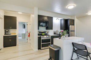A modern kitchen with dark cabinetry, stainless steel appliances, and a central island with seating. - Front Range, Rocky Mtn Nat'l Park Base: Golf Views (Loveland)