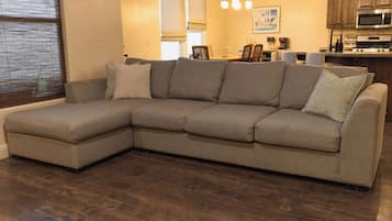 Ein Ecksofa in einem Wohnzimmer mit Holzboden.