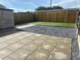 Ein gepflasterter Patio-Bereich mit Rasen und Holzzaun.