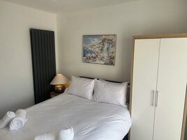 Ein Hotelzimmer mit einem Bett, einer Nachttischlampe, einem Gemälde und einem Kleiderschrank.