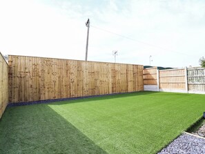 A fenced backyard with artificial grass and a wooden fence. - 6 Bastion Close (Prestatyn)