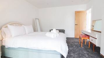 A bedroom with a bed, a bedside table, a chair, a mirror, and a door.