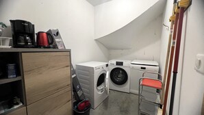 Une buanderie équipée d’un lave-linge, d’un sèche-linge et d’un petit chariot.