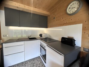 Eine kleine Küche mit Mikrowelle, Toaster und einer Uhr an der Wand.