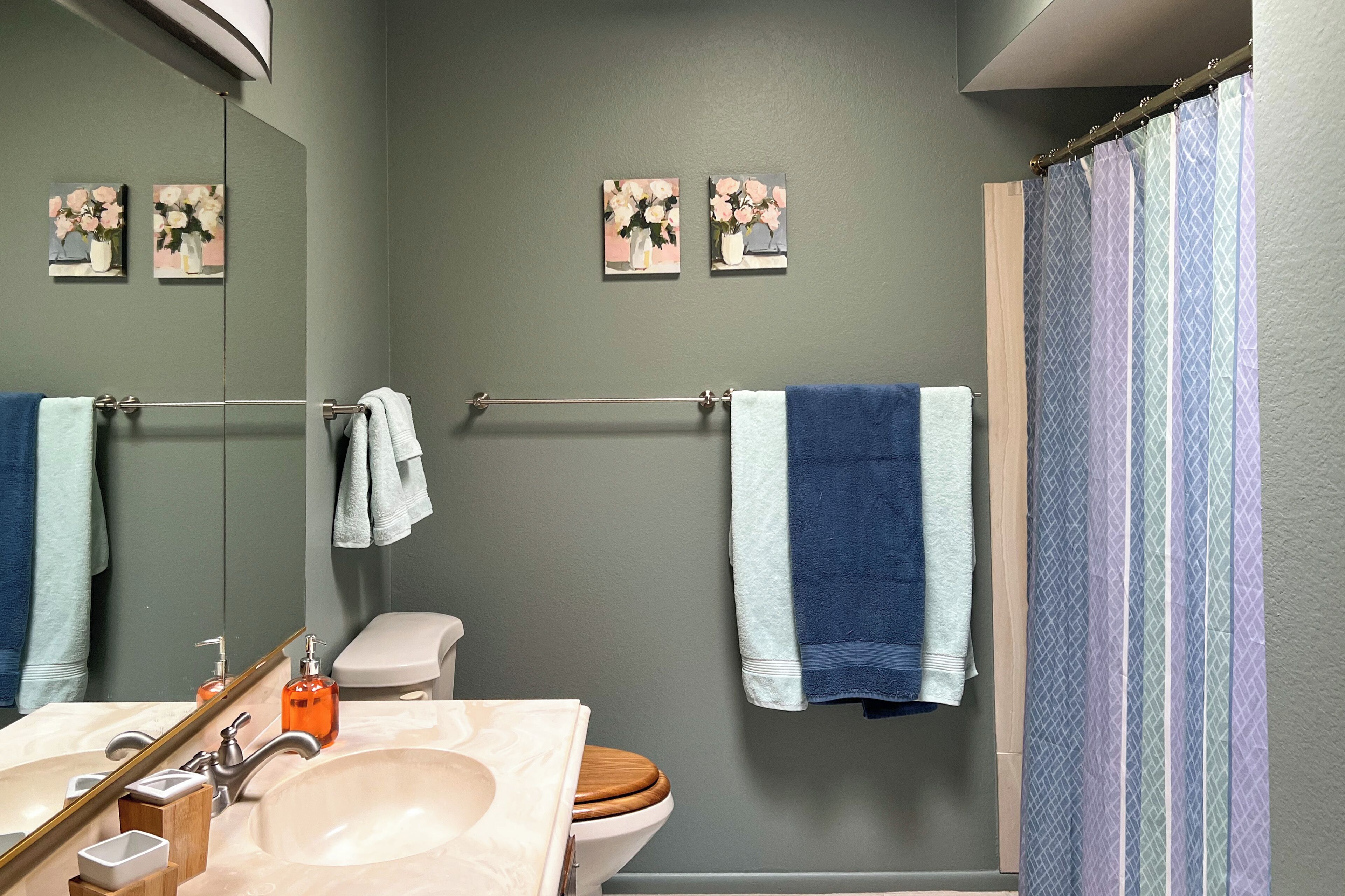 A bathroom with a sink, mirror, toilet, and shower curtain.