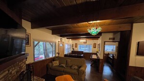 Ein gemütliches Wohnzimmer mit Kamin, Fernseher, Sofa und Holzboden.