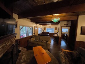 Ein gemütliches Wohnzimmer mit Kamin, Fernseher, Sofa und Holzboden.