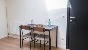 A small dining area with a table, two chairs, a kettle, a bottle of water, and a door. - 15-Min Walk to Ghent Center | Cozy Private Room (Ghent)