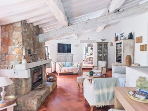 Ein gemütliches Wohnzimmer mit Kamin aus Stein, einem Flachbildfernseher und einem Essbereich mit Tisch und Stühlen.