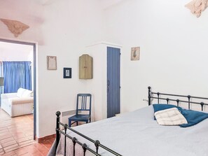 A bedroom with a bed, a chair, a wardrobe, and a door leading to another room. - Le Vieux Moulin by Interhome (Plan de la Tour)