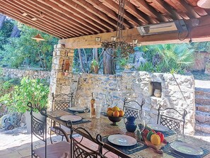 An outdoor dining area with stone walls, a wooden ceiling, and a hanging chandelier. - Le Vieux Moulin by Interhome (Plan de la Tour)