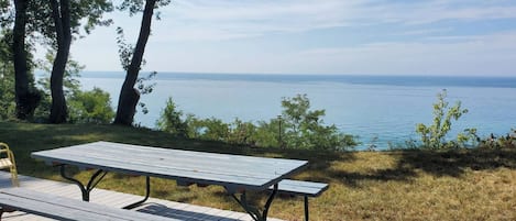 A picnic table with benches on a wooden deck overlooking a body of water.