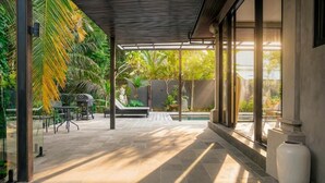 A covered outdoor area with a pool, seating, and tropical plants. - Kokokan Villa Ubud (Gianyar)