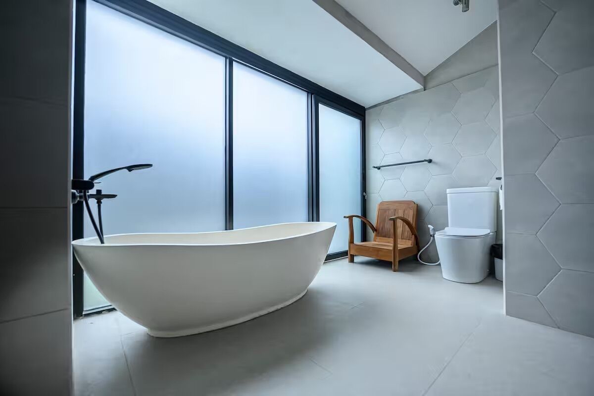 Une salle de bain moderne avec une baignoire sur pieds, une chaise en bois et des toilettes.