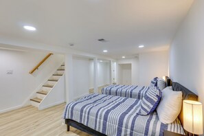 Ein Schlafzimmer mit einem Bett, einer Nachttischlampe, einer Holztreppe und einer Tür zu einem anderen Raum.