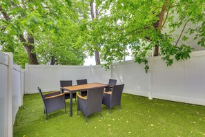 Eine Terrasse mit Tisch und Stühlen, umgeben von einem weißen Zaun und Bäumen.