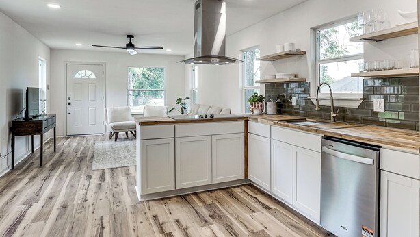 Una cocina moderna con armarios blancos, una campana de acero inoxidable y un lavavajillas.