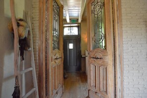 Un couloir étroit, avec des portes en bois et une échelle sur le côté gauche.