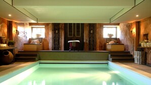 Piscina com escadas de acesso, paredes de madeira e janela com uma planta.