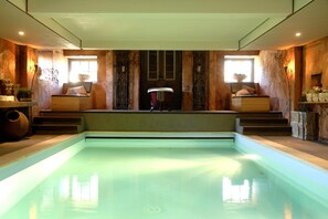 Une piscine avec des marches permettant d’y accéder, des murs en bois et une fenêtre ornée d’une plante.