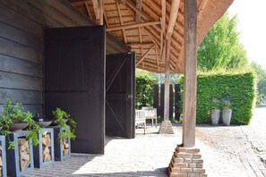 A covered outdoor area with a wooden structure, a bench, and potted plants. - Charming Home with Hot Tub (Alphen)
