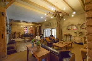 A rustic interior with wooden furniture, stone walls, and a chandelier. - Charming Home with Hot Tub (Alphen)