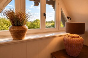 Ein Fenster mit einem Blumentopf und einer Lampe auf einem Holztisch.