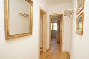 Ein Flur mit einem großen Spiegel, Holztüren und einem Fenster.