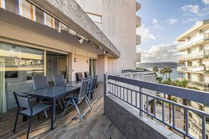 Un balcon avec une table et des chaises, une vue sur la mer et un immeuble doté de balcons.