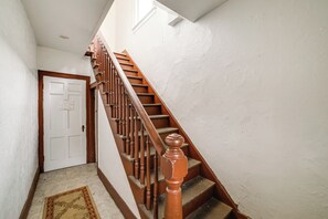 Eine Treppe mit Holzspindeln und einer Handlauf, die zu einer weißen Tür mit einem kreuzf örmigen Fenster führt.
