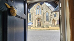 A doorway leading to a building with Gothic architecture, including pointed arches and stained glass windows. - Katie's Cottage (Church Stretton)