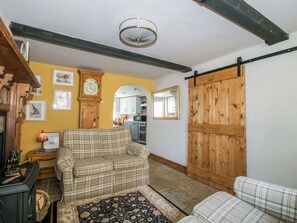 Ein gemütliches Wohnzimmer mit einem Karomuster-Sofa, einer Holzuhr und einem großen Spiegel.