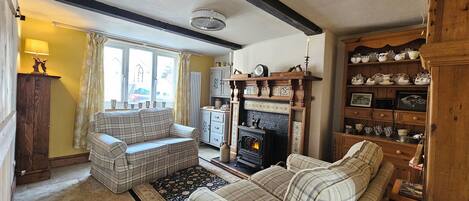 A cozy living room with a fireplace, a sofa, a rug, and a wooden cabinet with china.