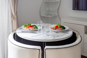 A round dining table with two plates of food, two glasses, and cutlery. - Family-Friendly Calpe Home with Pool (Calpe)