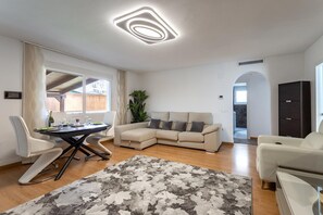 Ein modernes Wohnzimmer mit einem Ecksofa, einem Esstisch und einem großen Teppich.