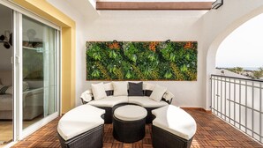 A balcony with a curved sofa, a round table, and a decorative wall. - Family-Friendly Calpe Home with Pool (Calpe)