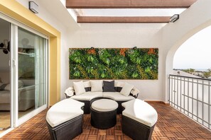 Ein Balkon mit einer gebogenen Couch, einem runden Tisch und einer Wandverzierungen.