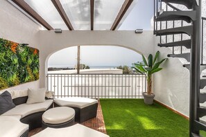 A balcony with a view of the sea, a green artificial grass area, and a seating arrangement with cushions. - Family-Friendly Calpe Home with Pool (Calpe)