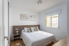 A bedroom with a bed, bedside table, lamp, artwork, window, and a door. - Family-Friendly Calpe Home with Pool (Calpe)