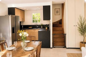 A modern kitchen with a central island, wooden cabinets, and a black countertop. - House with garden near the beach – pool and tennis (Deauville)