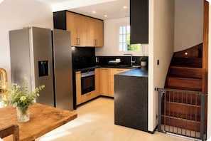 A modern kitchen with stainless steel appliances, wooden cabinets, and a black countertop island. - House with garden near the beach – pool and tennis (Deauville)