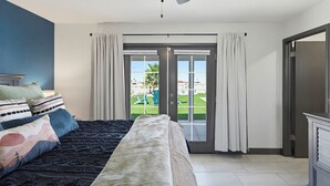 A bedroom with a bed, curtains, a ceiling fan, and a view through a glass door. - Pool, Game Room & Lake View! Modern Havasu Home (Lake Havasu City)