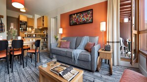 Un salon moderne avec un canapé gris, une table basse en bois et des fauteuils orange.