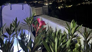 A rooftop terrace with a view of a cityscape at night, including buildings and distant mountains. - Felicita – Cascata Terrace with Lake View (Lecco)