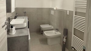 A modern bathroom with a skylight, a sink, a bidet, and a toilet. - Felicita – Cascata Terrace with Lake View (Lecco)