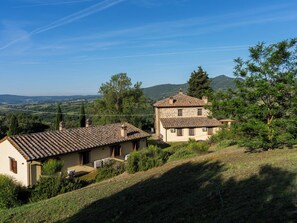 A two-story stone house with a tiled roof, surrounded by greenery and hills in the background. - "Poggio del Pero" by Interhome (Panicale)