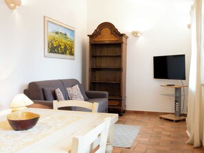 A living room with a sofa, a television, a wooden bookshelf, and a dining table. - "Poggio del Pero" by Interhome (Panicale)