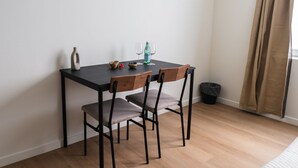 A small dining area with a table, chairs, a vase, a bottle, and a glass. - In the Heart of Ghent | Charming Private Room (Ghent)